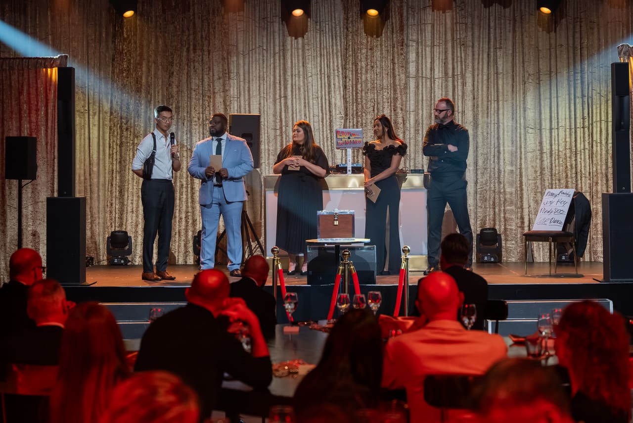 Speakers on the gala stage in front of a lit curtain